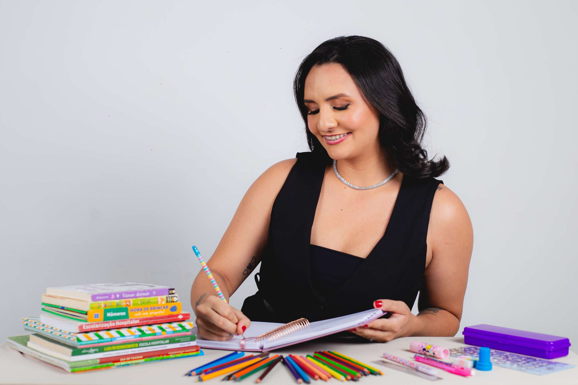 Retrato profissional de mulher escrevendo à mesa com livros